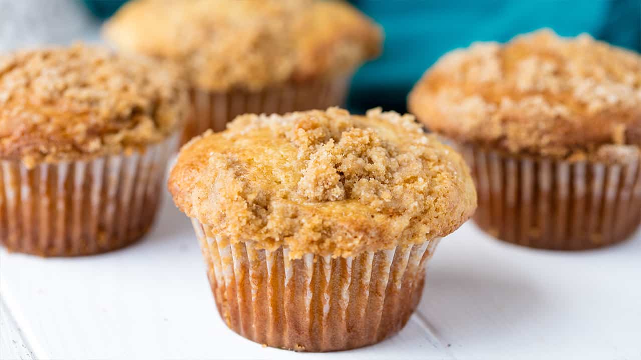 Close-up view of Sour Cream Coffee Cake Muffins on white painted wood table top.