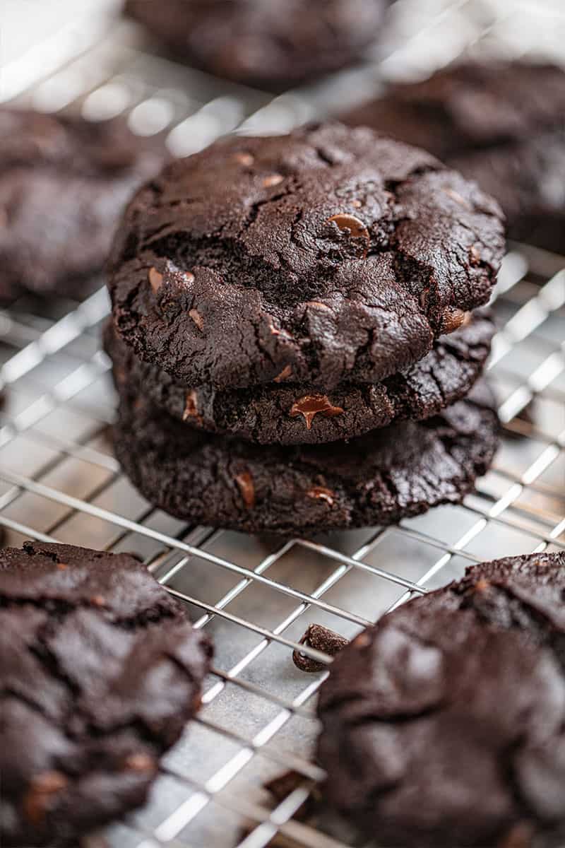 stack of 3 chocolate cookies on a wire cooling rack