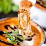 Caprese soup in a soup bowl with spoon taking a scoop