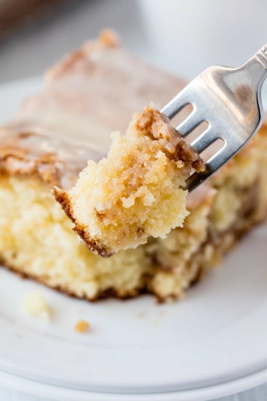 Close up of a fork with some coffee cake on it.