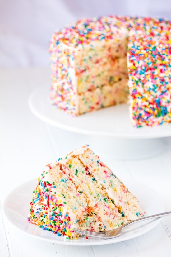 Slice of Funfetti Birthday Cake with a bite taken out of it on a plate with a fork on it.
