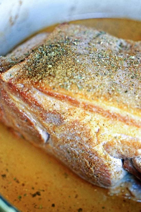 Photo of pork slow cooking in its juices and oil.