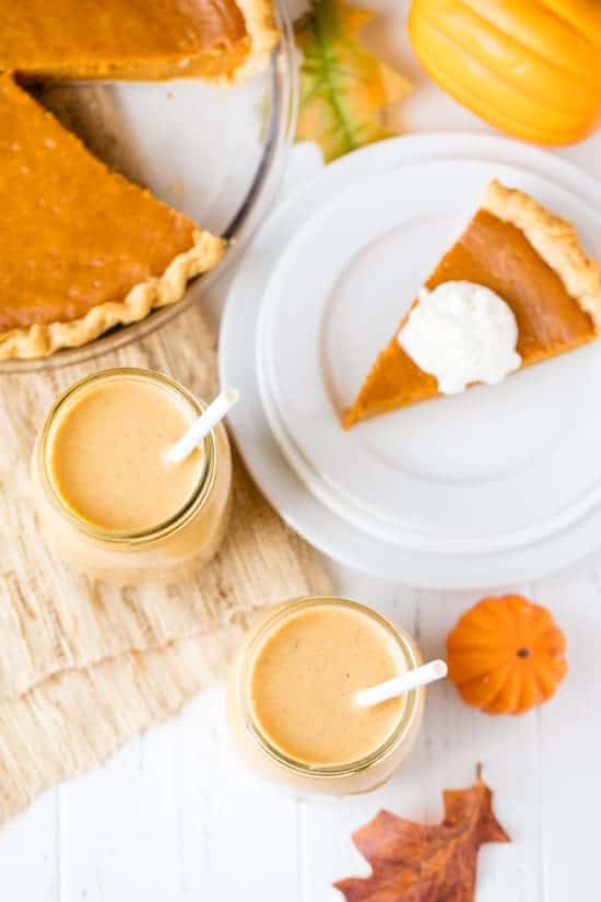 Bird's eye view of pumpkin pie smoothies sitting next to a slice of pumpkin pie and a pumpkin pie.