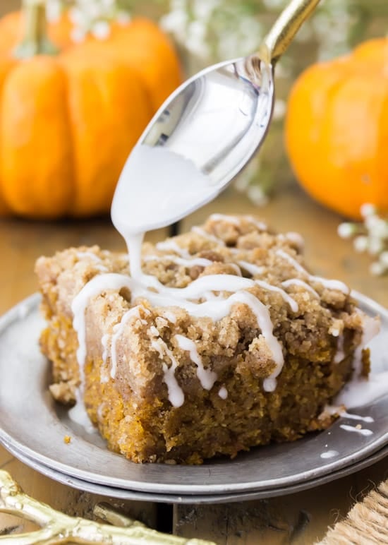 Spoon drizzling on the frosting on a pumpkin crumb cake. 