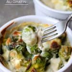 A fork lifts a bite of Brussel Sprouts Au Gratin from a bowl