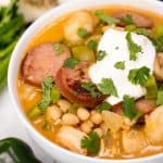 cajun white chicken chili with sour cream and cilantro in a white bowl