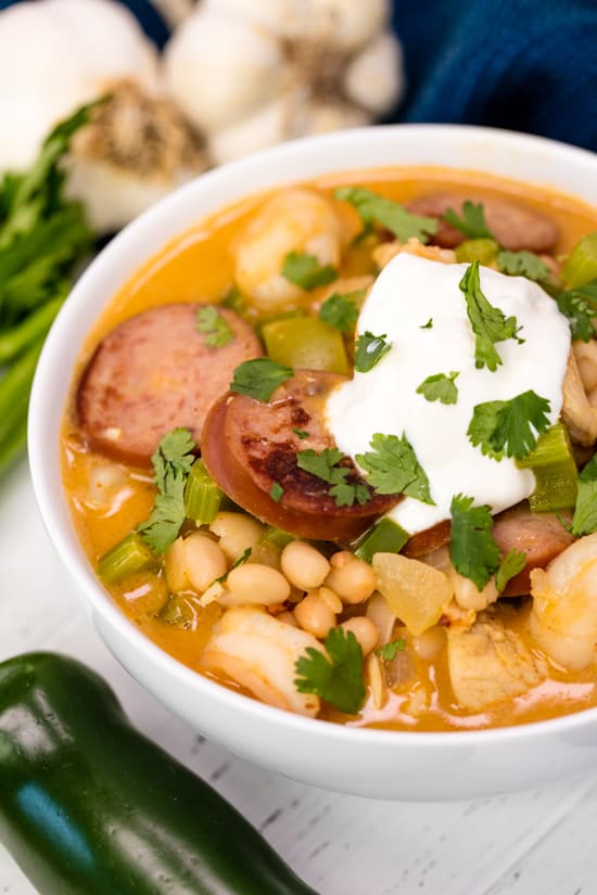 white chicken chili with sour cream and cilantro on top in a white bowl