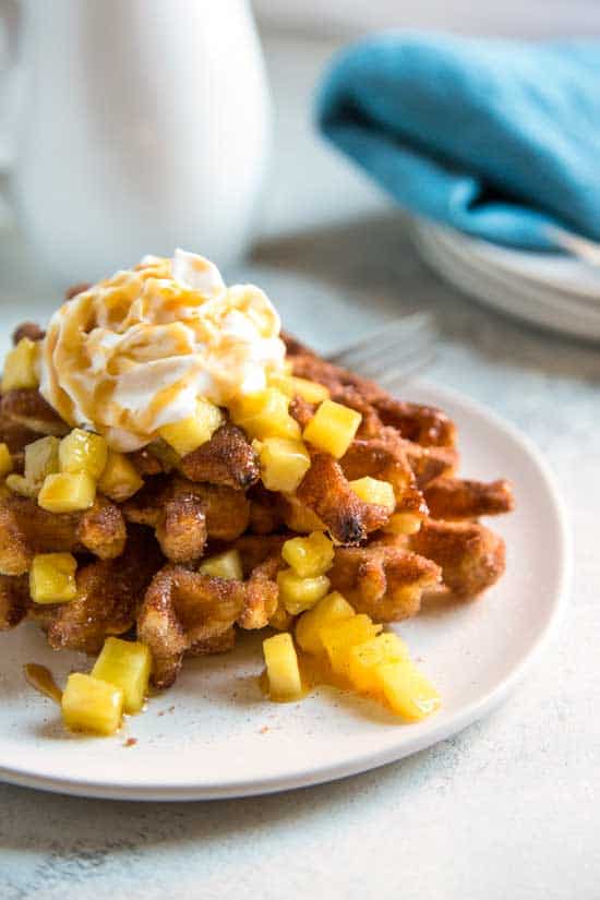 Churro Waffles topped with pineapple, a dollop of whipped cream and drizzled with caramel