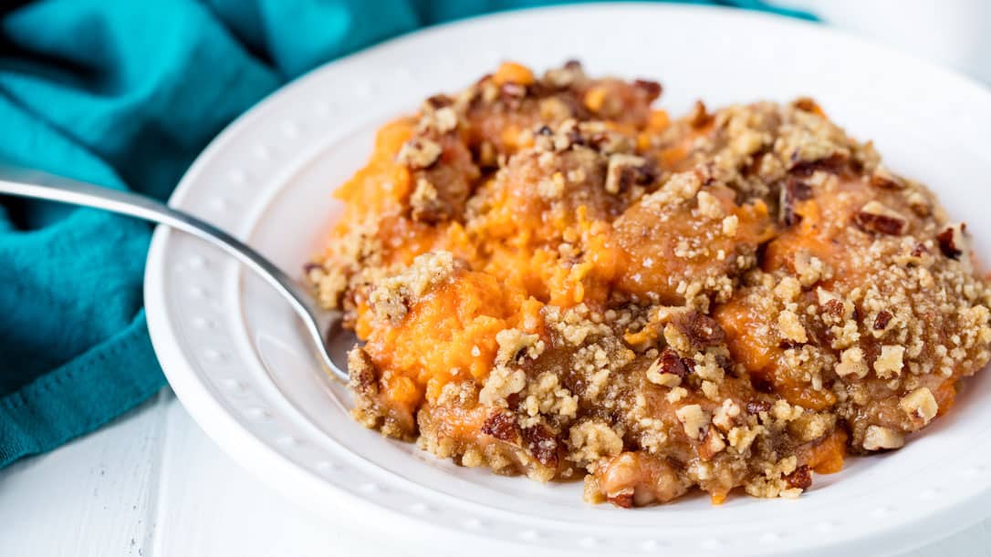 A plate full of sweet potato casserole with brown sugar and pecans