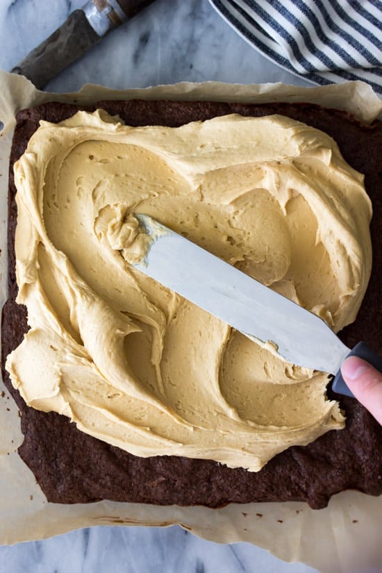 Rachel spreads peanut butter frosting onto brownies