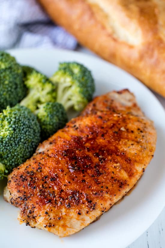 A seasoned, baked pork chop served with broccoli on a plate