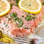 Easy Garlic Herb Baked Salmon topped with freshly chopped parsley and slices of lemon