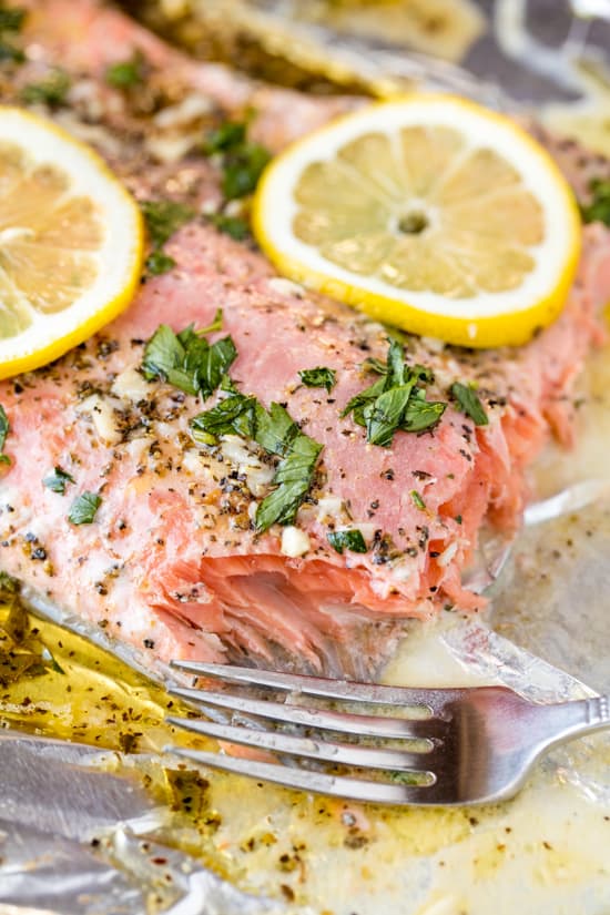 Easy Garlic Herb Baked Salmon topped with freshly chopped herbs, garlic and slices of lemon