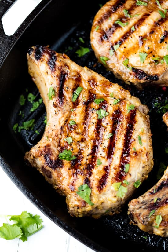 Pan-Grilled Pork Chops in a skillet topped with chopped fresh parsley