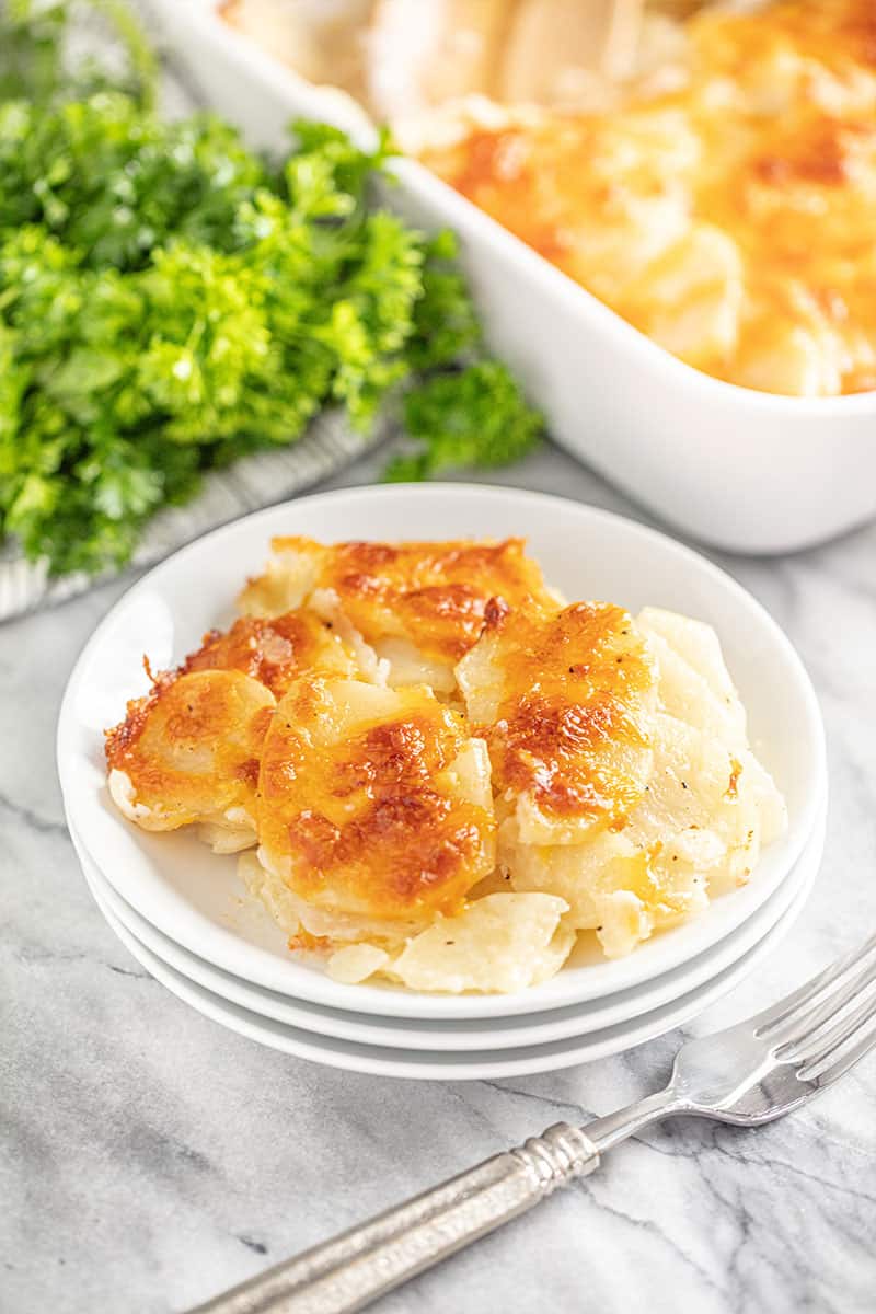 Scalloped Potatoes served up on a stack of white plates.