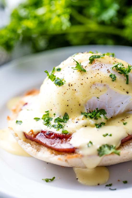 Perfect Eggs Benedict served on a plate, garnished with fresh chopped parsley