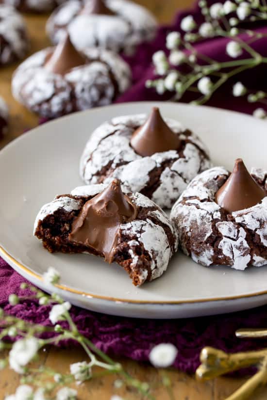 chocolate kiss cookies on a white plate. One has a bite taken out. 