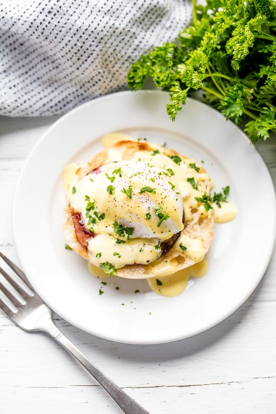 Perfect Eggs Benedict served on a plate, garnished with fresh chopped parsley