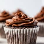 Chocolate cupcakes with chocolate frosting sitting on the counter.