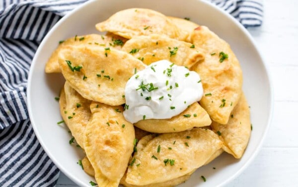 Potato and Cheese Pierogis in a bowl with a dollop of sour cream