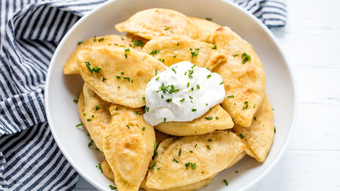 Potato and Cheese Pierogis in a bowl with a dollop of sour cream