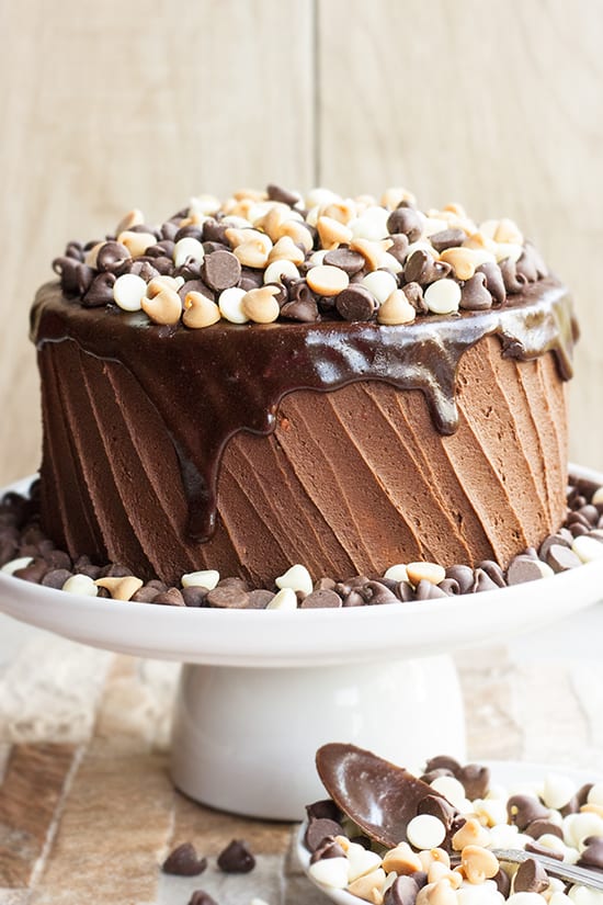 Coffee Chocolate Cake with chocolate buttercream and topped off with espresso ganache and chocolate, white chocolate, and butterscotch chips, served on a white cake stand