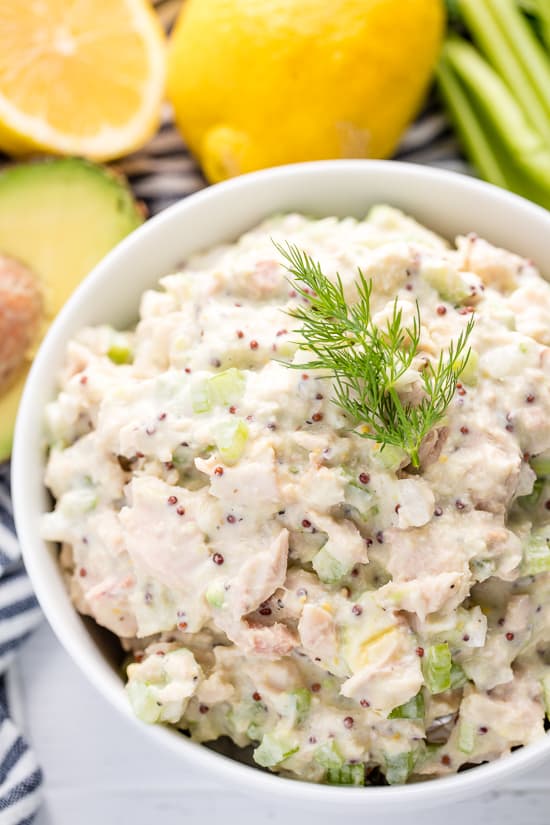 Tuna Salad in a white bowl topped with a sprig of dill.