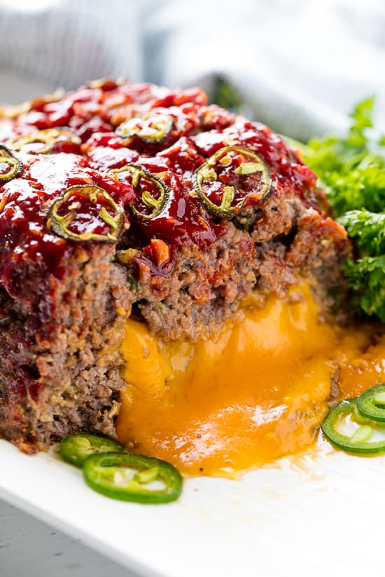 Jalapeno Cheddar Stuffed Meatloaf cut in half with the cheddar cheese oozing out.