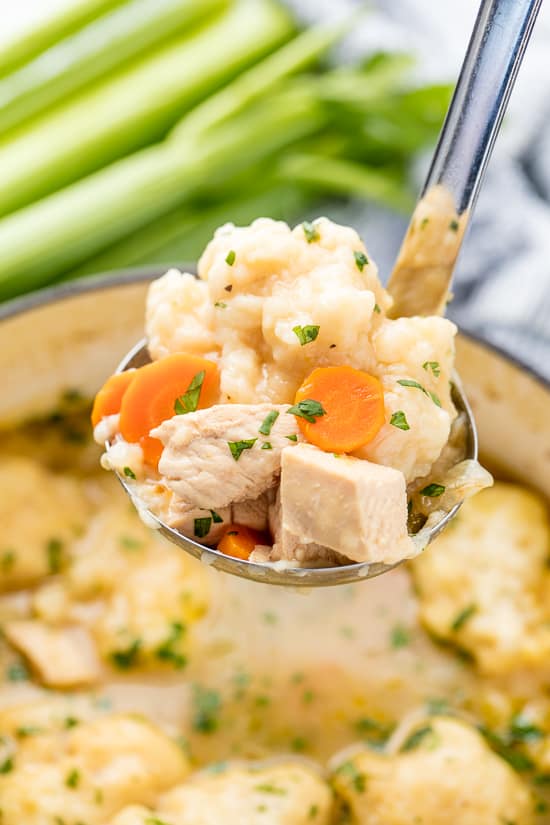 A ladle of Easy Chicken and Dumplings with cubes of chicken, sliced carrots and dumplings