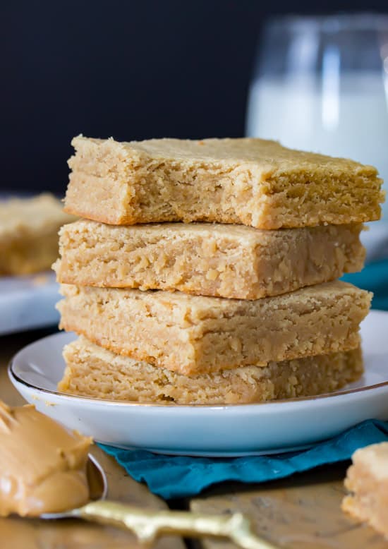 Peanut Butter Blondies stacked on a plate. One with a bite taken out of it