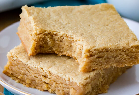 Peanut Butter Blondies stacked on a plate. One with a bite taken out of it