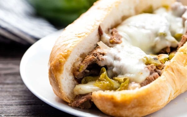 Angled view of Philly Cheese Steak with green bell peppers and melted Kraft provolone cheese on a hoagie roll.