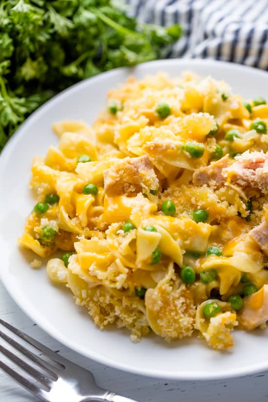 Tuna Casserole served up on a white plate with parsley and a handtowel in the background.