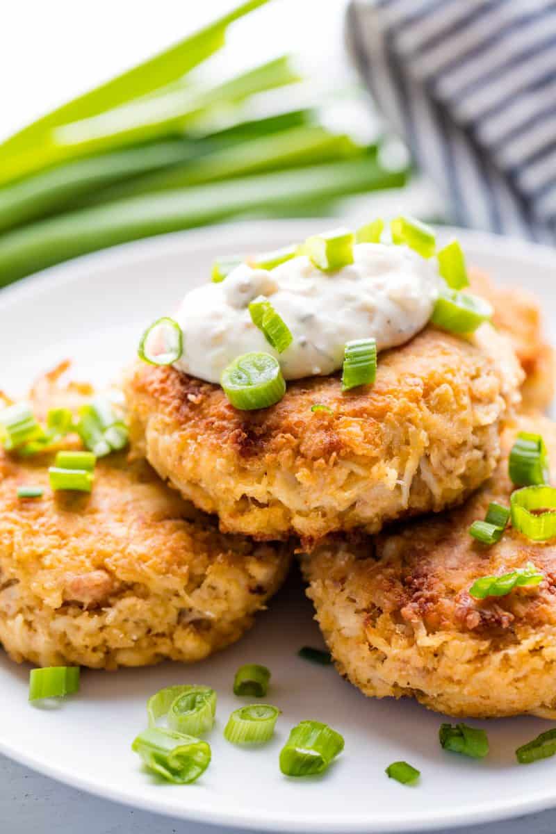 Three Crab Cakes stacked into a pyramid with tartar sauce on the top.