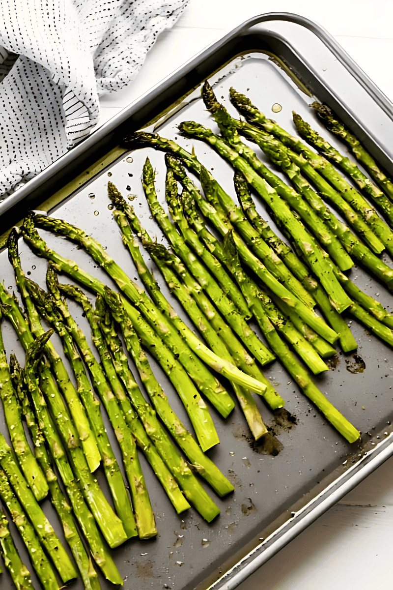 An overhead view of asparagus on a baking sheet for roasting.