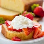 Slice of Pound Cake with sliced strawberries and whip cream on it.