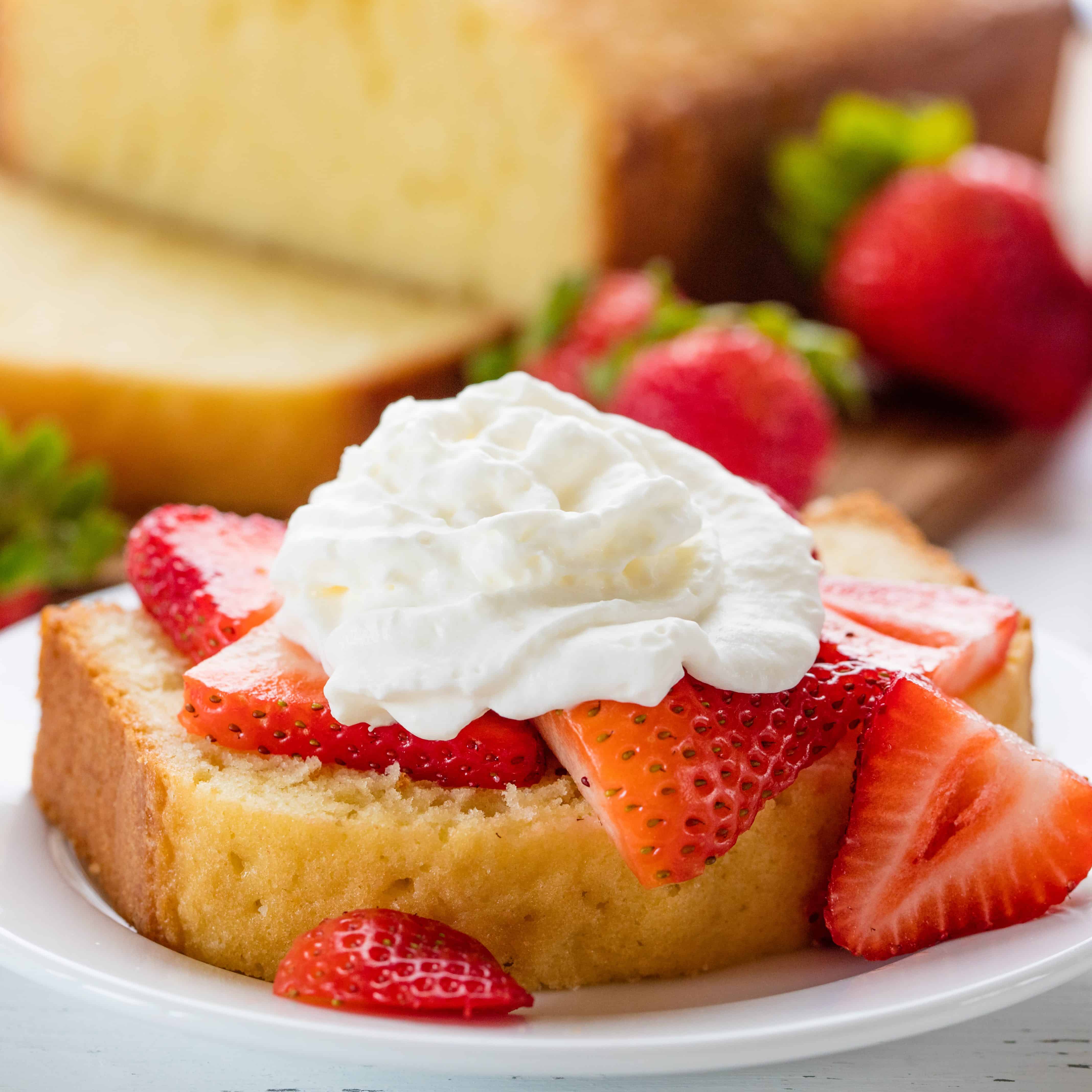 Slice of Pound Cake with sliced strawberries and whip cream on it.