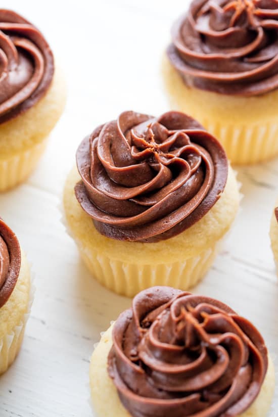 Vanilla Cupcakes with chocolate frosting sitting on a white counter.