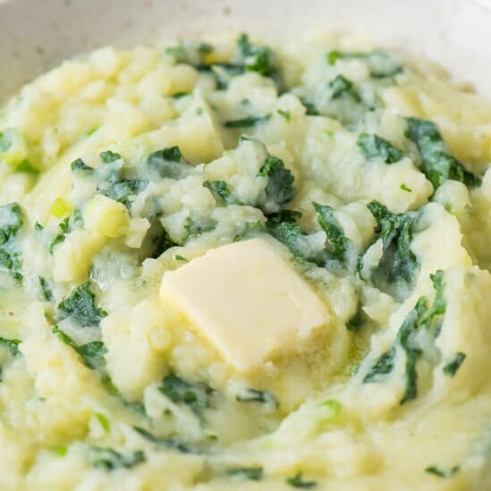 A close up view of colcannon in a bowl with butter melting on top.