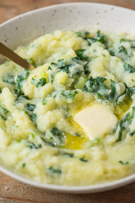 Bowl full of colcannon with a metal spoon in it.