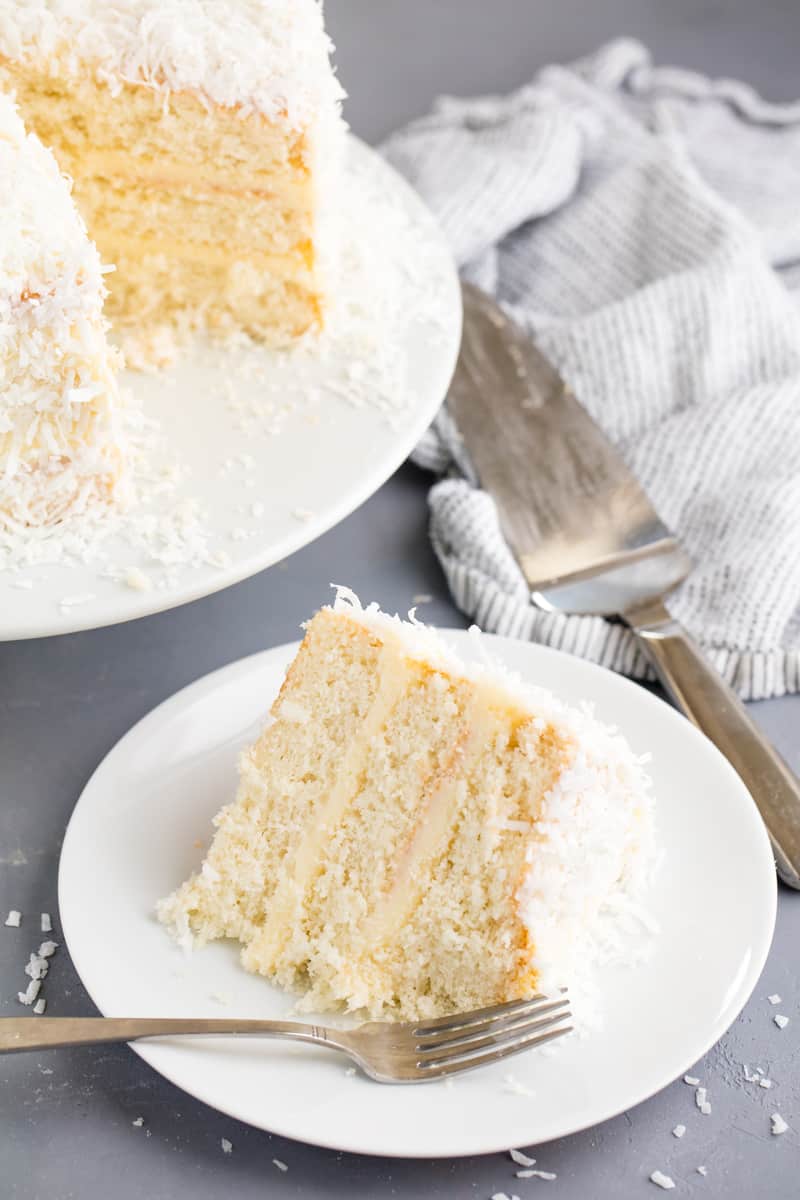 A slice of Coconut Cake on a white plate with fork