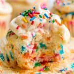 Close up of a funfetti birthday cupcake with the wrapper undone and a bite taken out of it.