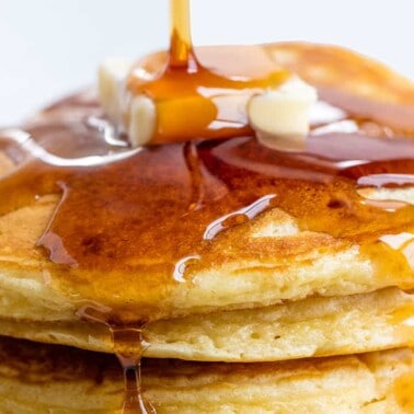 Close up Pancakes topped with syrup and a pad of butter.