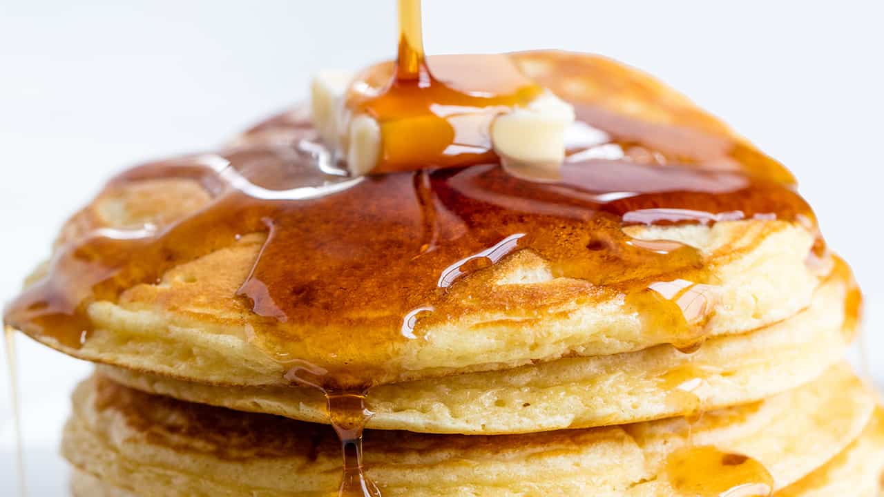 Close up Pancakes topped with syrup and a pad of butter.
