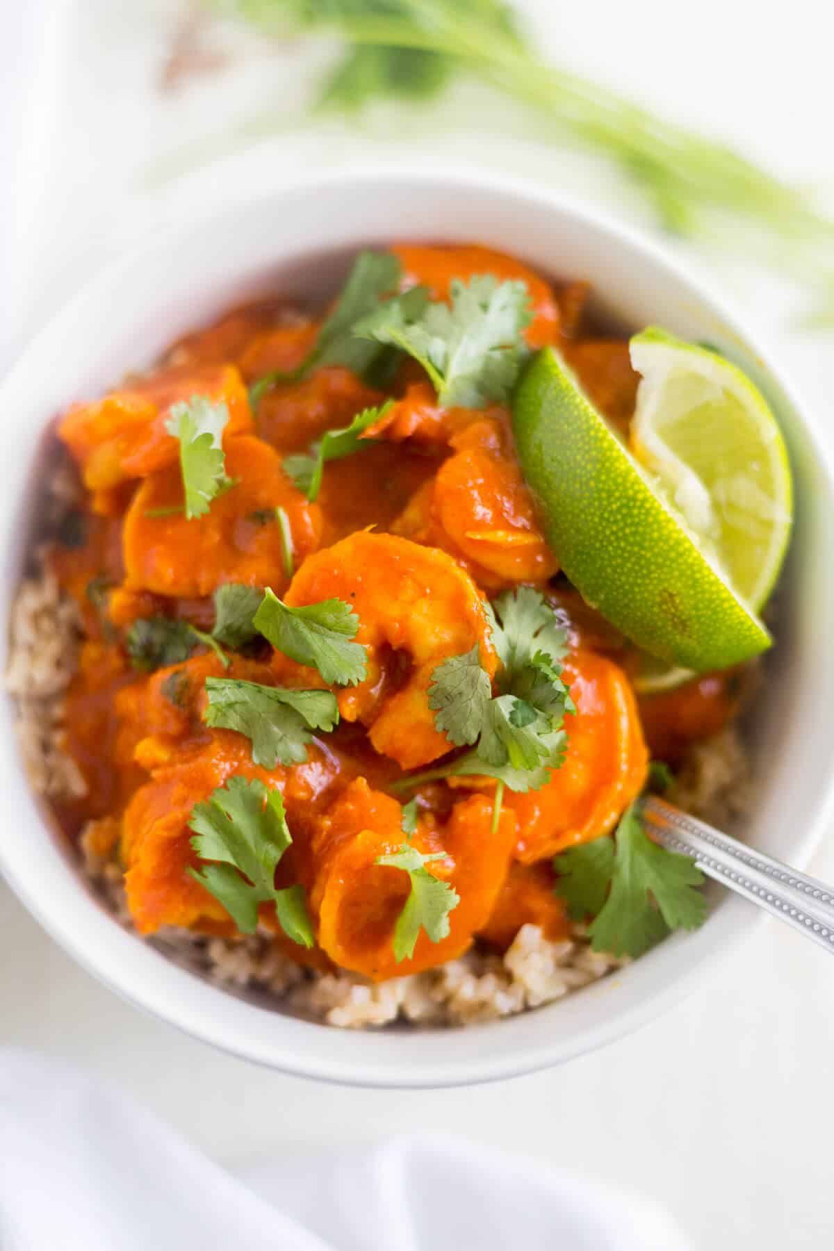 red curry in a white bowl with lime wedges