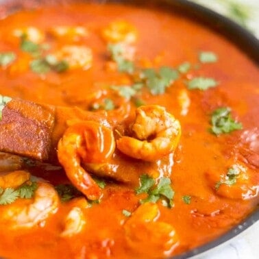 Red shrimp curry in a black skillet.