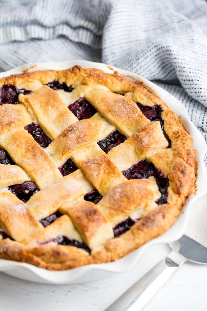 Blueberry Pie in a pie pan sitting on a countertop.