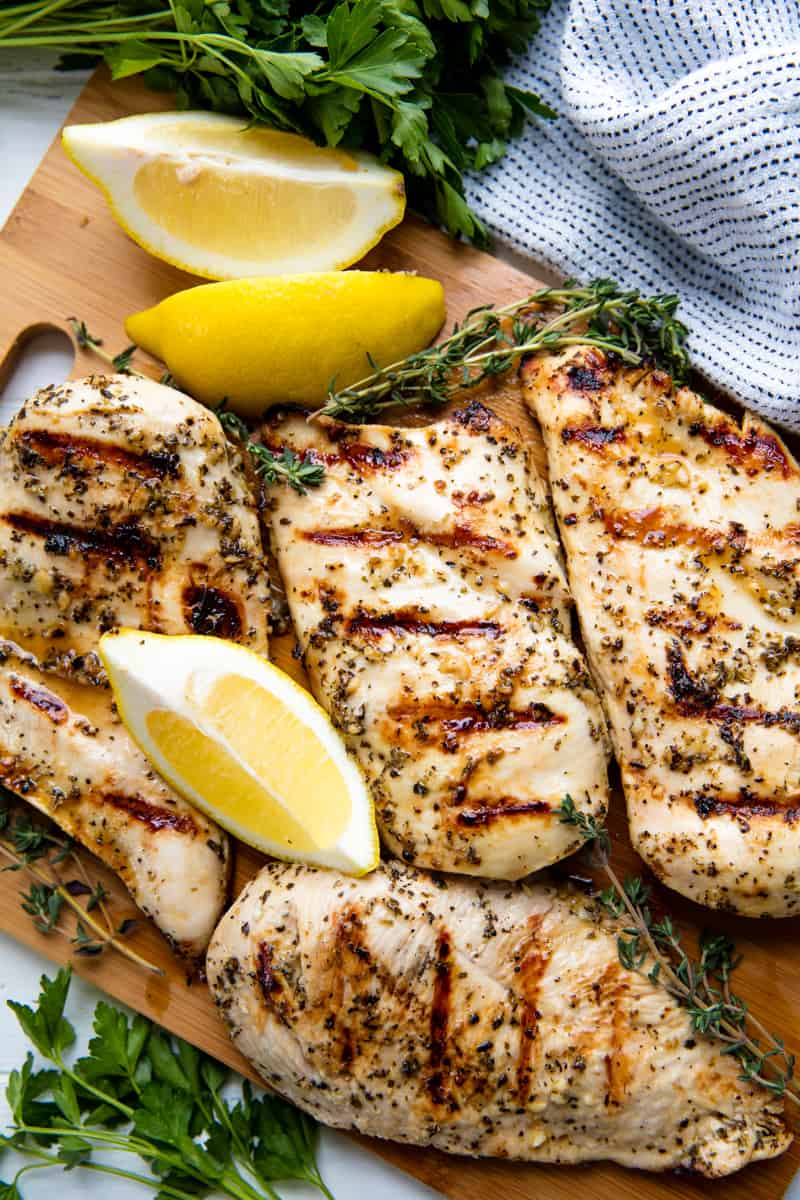 Grilled Chicken on a cutting board with lemon wedges.