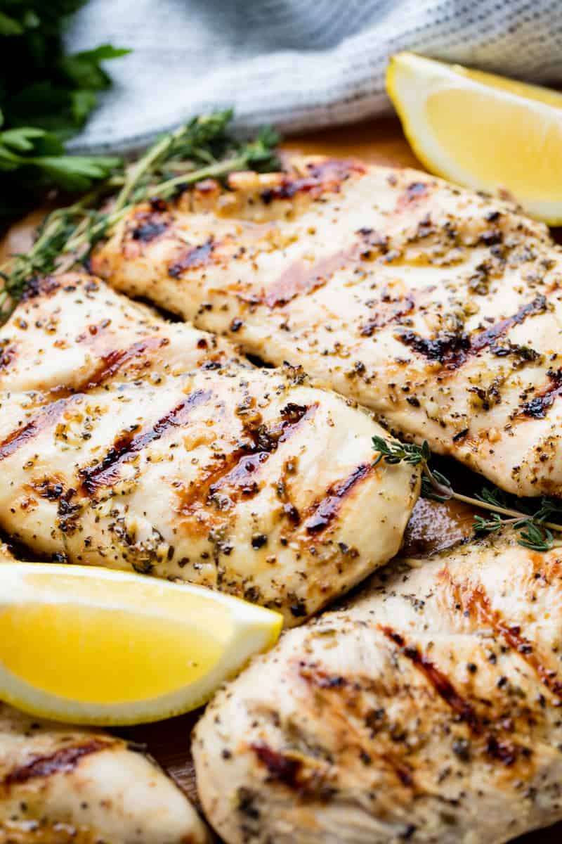 Close up of Grilled Chicken Breasts with lemon wedges.