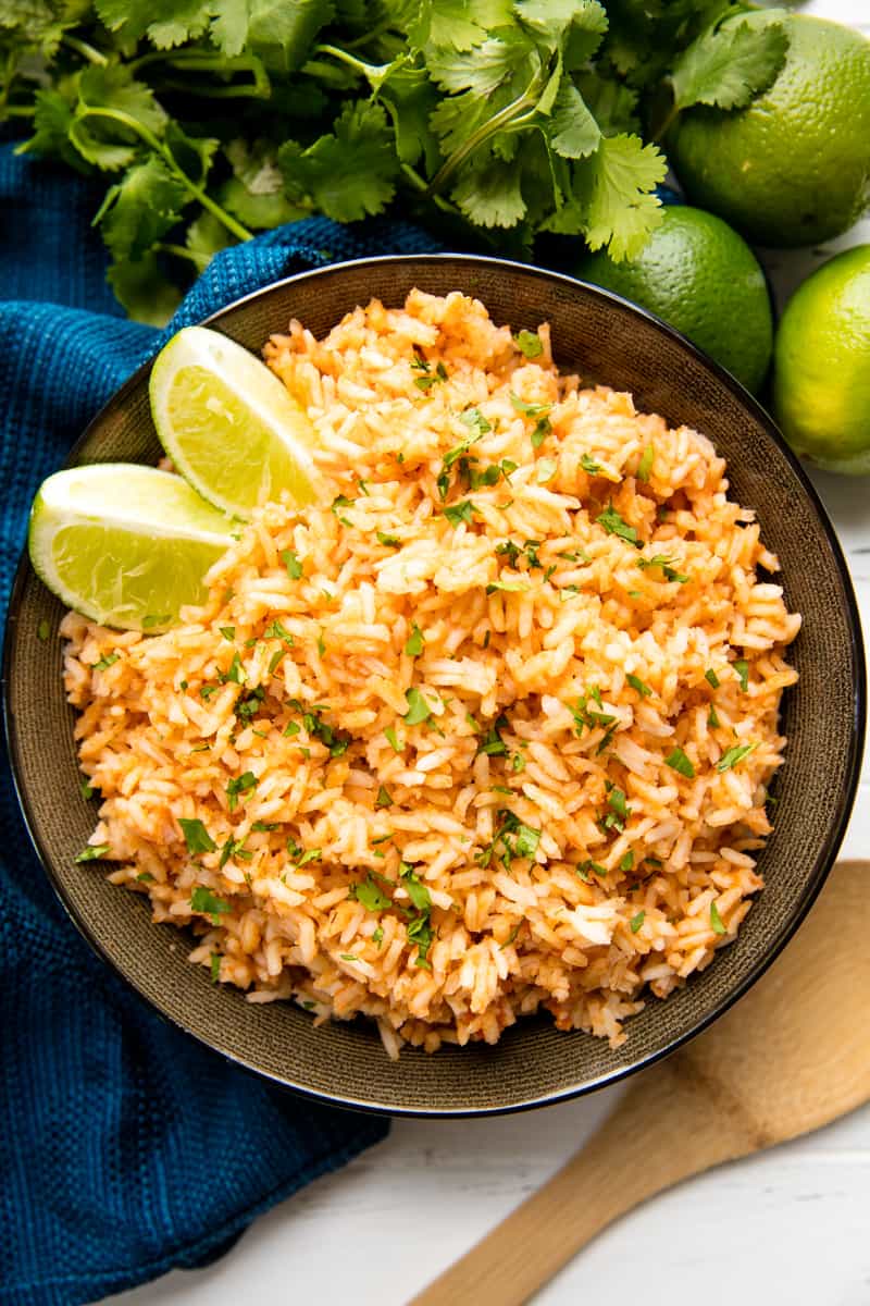 Bird's eye view of Spanish Rice with two lime wedges in it in a dark bowl. 